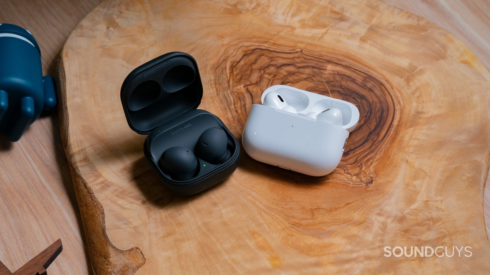 Các hộp mở của Samsung Galaxy Buds 2 Pro nằm cạnh Apple AirPods Pro (thế hệ thứ 2) trên bề mặt gỗ