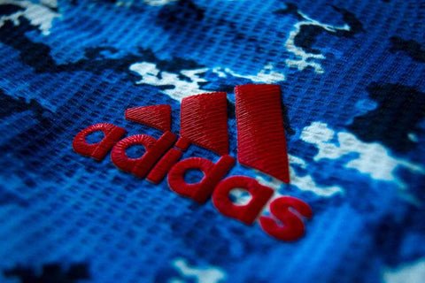 Logo adidas chính hãng trên áo đấu, thể hiện sự tỉ mỉ và đồng nhất về phông chữ, chi tiết