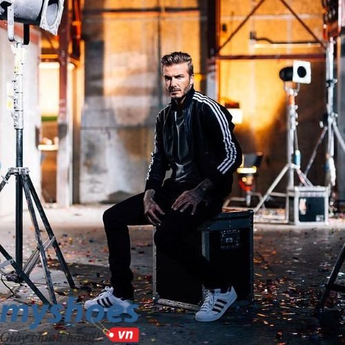 Một người phụ nữ nổi tiếng trong bộ trang phục sành điệu với áo khoác da, quần jean và giày Adidas Superstar trắng