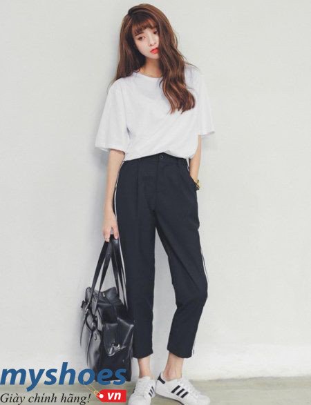 Người đàn ông mặc quần baggy đen, áo thun trắng và giày Adidas Superstar trắng, tạo vẻ ngoài thoải mái