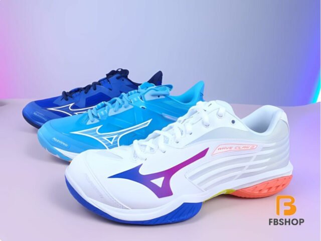 Một người chơi cầu lông đang cầm đôi giày Mizuno trên sân, thể hiện sự thoải mái và sẵn sàng cho trận đấu.