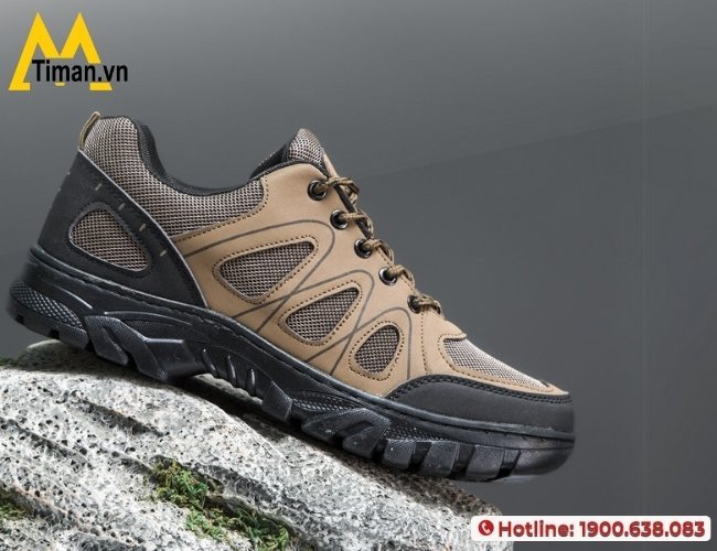 Một người đàn ông đang kiểm tra chi tiết đường may trên đôi giày thể thao màu nâu của mình, biểu tượng cho cách chọn giày sneaker nam nâu chất lượng cao.