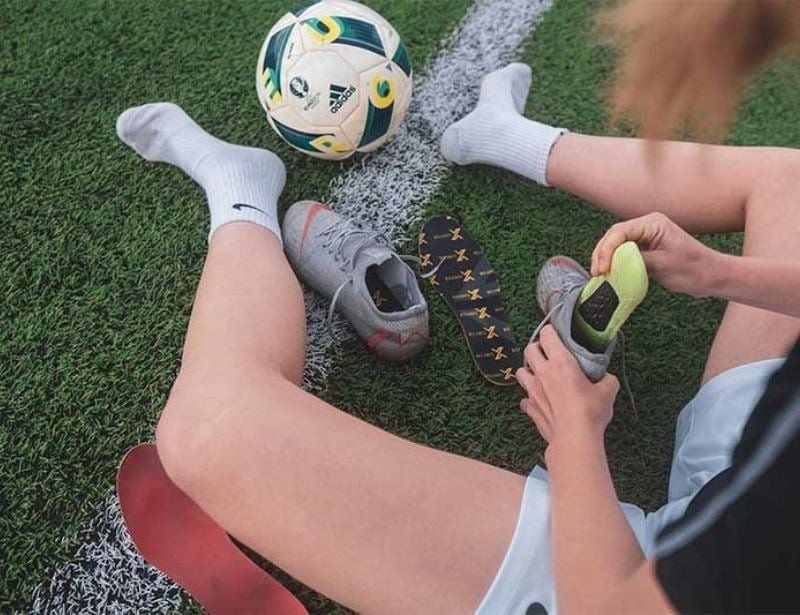 Cầu thủ bóng đá với vẻ mặt đau đớn vì tình trạng đau gót chân khi mang giày không phù hợp