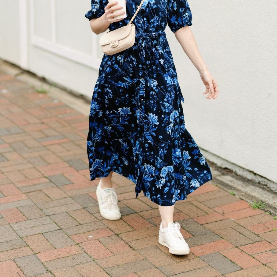 Cô gái dạo biển với váy maxi họa tiết và đôi giày sneaker màu trắng, tạo nên vẻ ngoài thoải mái của phong cách giày thể thao mặc váy