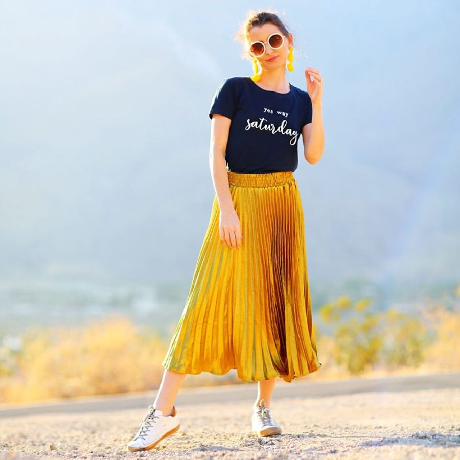 Cô gái dạo phố với chân váy xếp ly màu tím và giày sneaker trắng, thể hiện phong cách giày thể thao mặc váy nữ tính và năng động