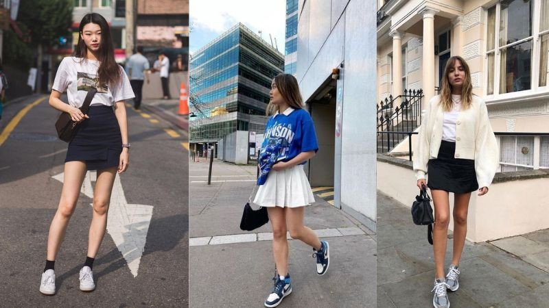 Cô gái mặc áo thun trắng và chân váy denim xanh, kết hợp với giày thể thao màu kem, tạo nên phong cách trẻ trung và thanh lịch