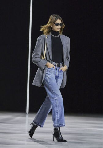 Cô gái mặc quần skinny jeans đen, áo khoác denim và giày boot nữ cổ thấp màu đen, phù hợp phong cách đi chơi hoặc tiệc nhẹ ngoài trời.