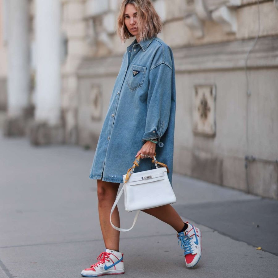 Cô gái mặc váy denim và áo len trắng với giày thể thao trắng