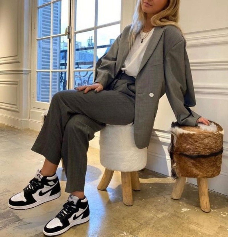 Cô gái mặc vest màu xám phối áo phông đen và giày Jordan đen trắng