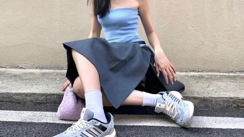 Cô gái trẻ trung mặc chân váy xòe và giày sneaker độn đế trắng