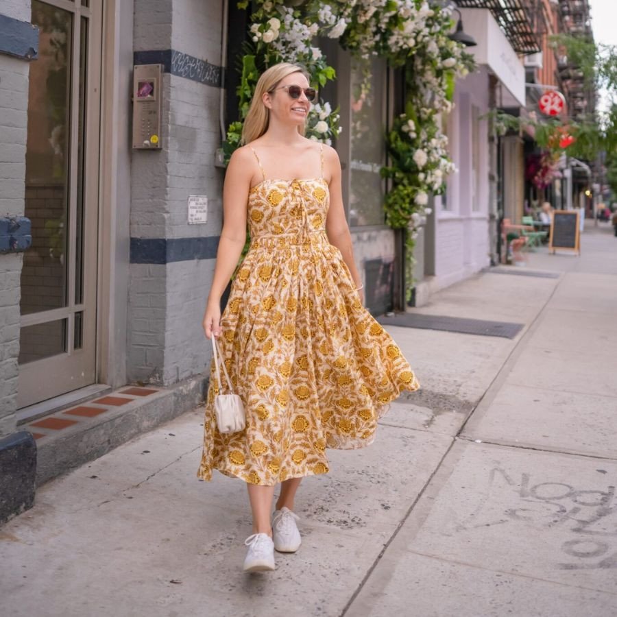 Cô gái xinh xắn với váy xòe họa tiết và đôi sneaker màu trắng, tạo nên outfit giày thể thao mặc váy trẻ trung