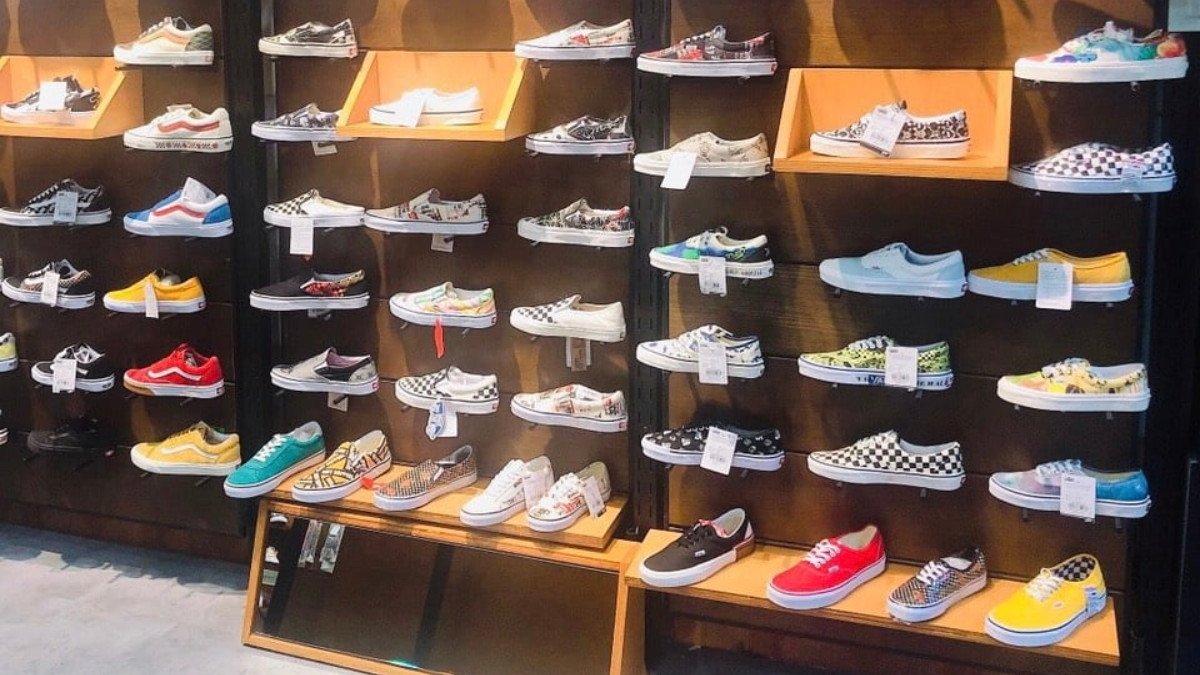 Dãy giày New Balance nhiều màu sắc được trưng bày gọn gàng trên kệ gỗ trong một cửa hàng giày hiện đại tại Hà Nội, sẵn sàng cho khách hàng lựa chọn.