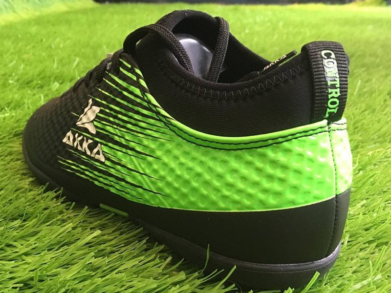 Đôi giày đá banh màu đen đang được đặt trên một nền cỏ