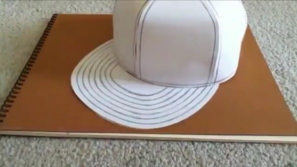Dùng băng dính cố định lưỡi trai vào thân mũ giấy
