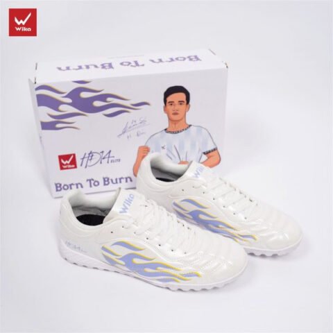 Giày đá bóng màu trắng trên sân cỏ nhân tạo