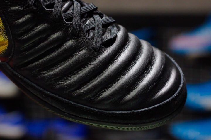 Hình ảnh cận cảnh một đôi giày đá bóng hỗ trợ chích mũi với phần mũi giày được gia cố chắc chắn.