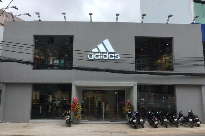 Hình ảnh cửa hàng Adidas tại Đà Lạt, với logo ba sọc nổi bật và không gian trưng bày giày hiện đại.