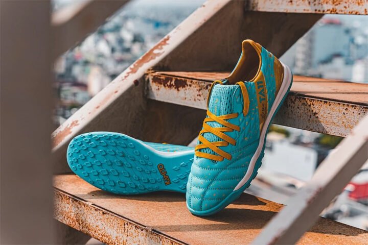 Hình ảnh một đôi giày đá bóng Kamito TA11 Pro đinh TF màu xanh ngọc vàng, nổi bật với lưỡi gà liền dệt kim và đế ngoài bám sân.