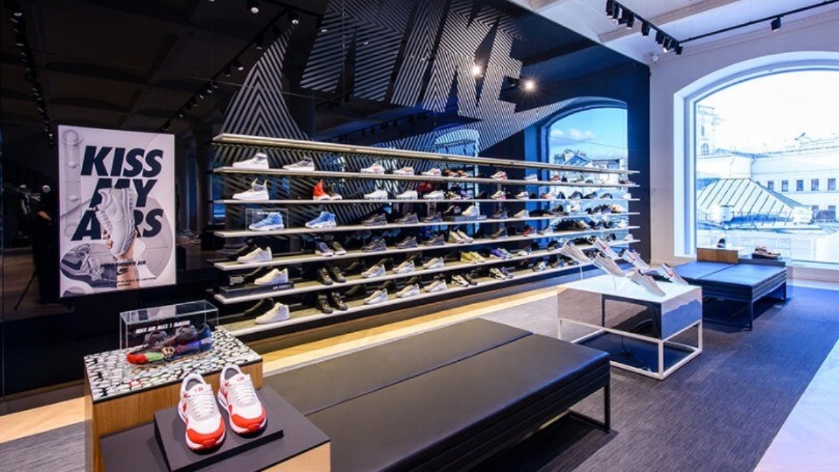 Kệ trưng bày đa dạng các mẫu giày New Balance màu sắc bắt mắt trong một không gian cửa hàng được chiếu sáng tốt, thu hút sự chú ý của người mua sắm.