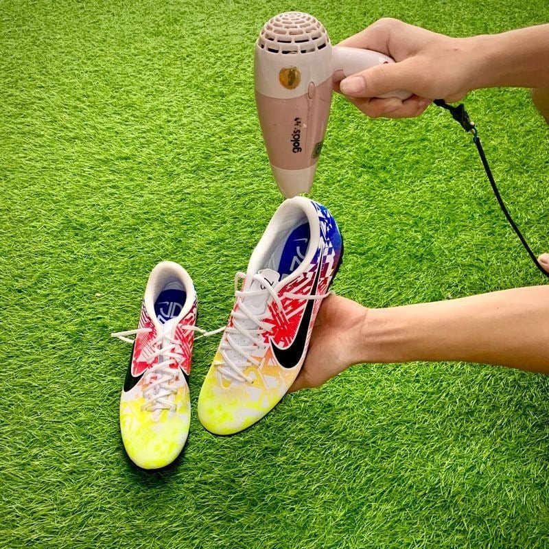 Làm mềm giày đá bóng bằng máy sấy để tránh gây đau gót chân và mang lại sự thoải mái