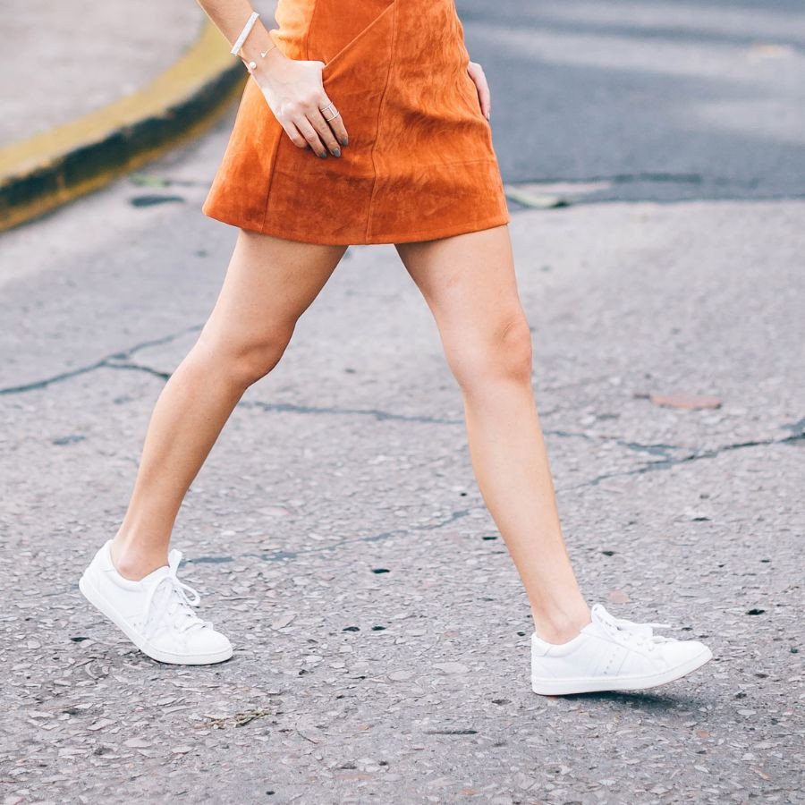 Một cô gái đang đi dạo với chân váy chữ A và giày sneaker trắng, minh họa sự năng động của phong cách giày thể thao mặc váy