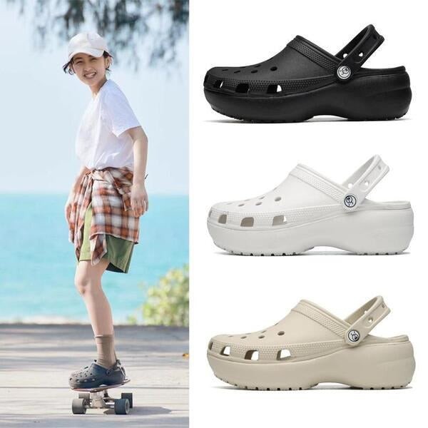Một cô gái đang đi giày Crocs thời trang màu xanh pastel trên bãi biển