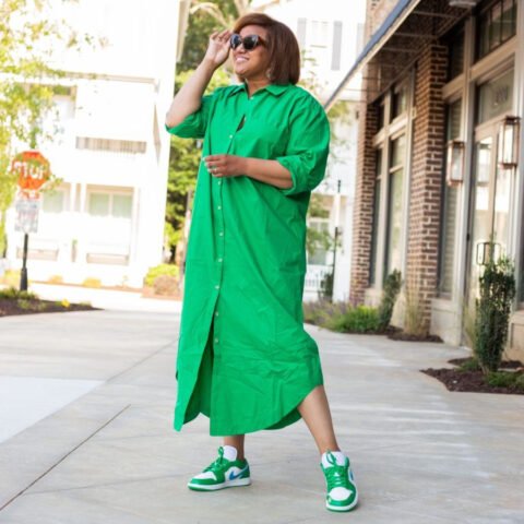 Một cô gái đang tạo dáng với chiếc váy đen và giày sneaker trắng, thể hiện phong cách giày thể thao mặc váy năng động