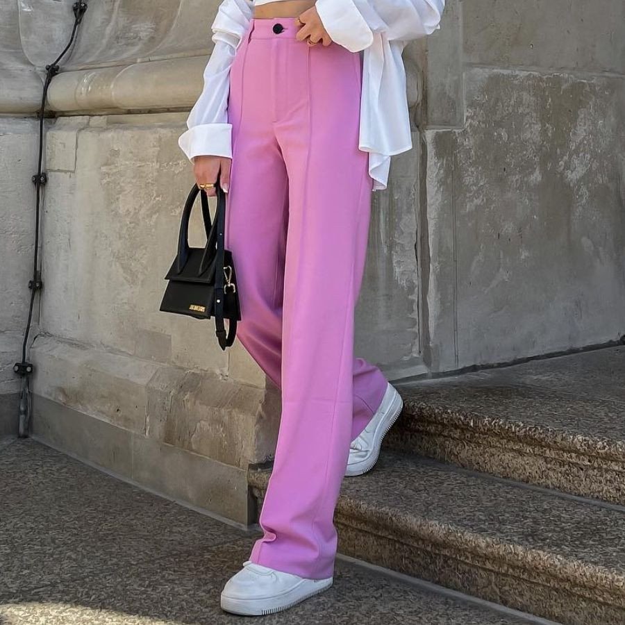 Một cô gái mặc quần ống loe đen và giày sneaker trắng cổ điển, khoe phong cách trẻ trung, năng động