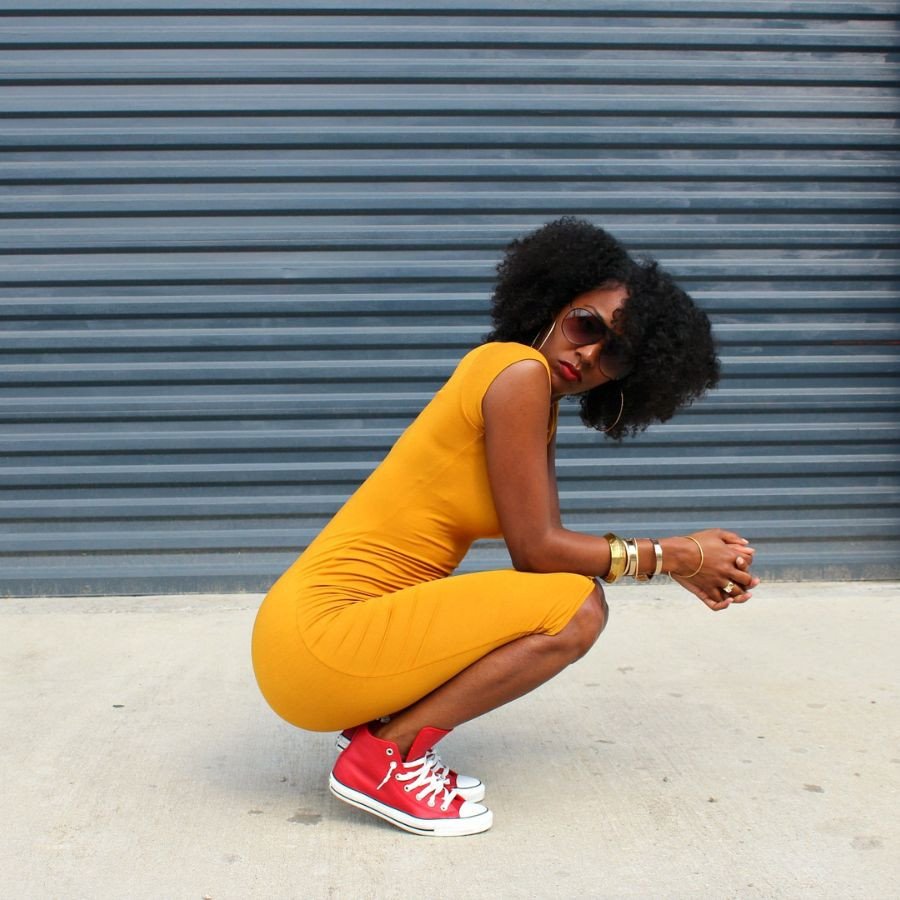 Một cô gái tạo dáng với váy body ôm sát và giày sneaker màu kem, thể hiện sự quyến rũ và năng động của giày thể thao mặc váy