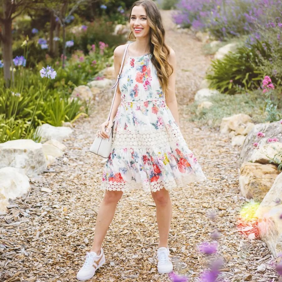 Một cô gái tạo dáng với váy hoa và giày sneaker màu xanh ngọc, thể hiện vẻ đẹp nữ tính của phong cách giày thể thao mặc váy