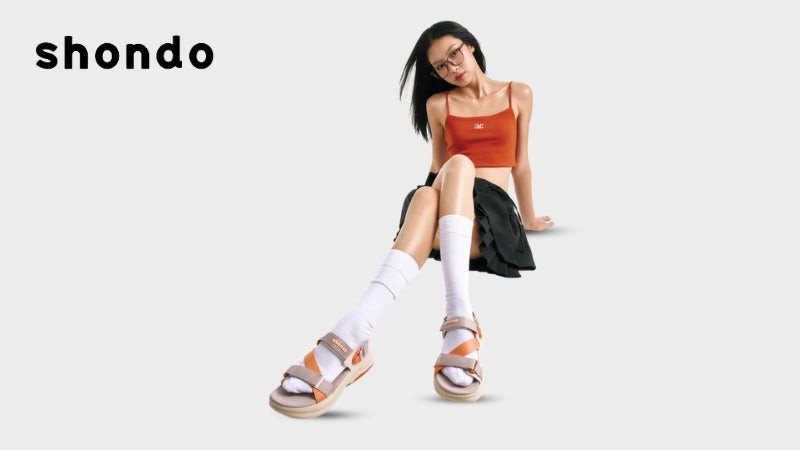 Một cô gái với chân váy chữ A họa tiết hoa, áo hai dây màu trắng và sandal quai mảnh màu nâu, tạo nên vẻ ngoài tươi tắn cho mùa hè.