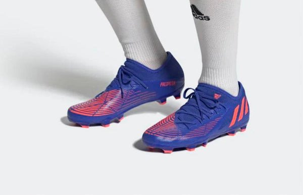 Một đôi giày Adidas Predator màu xanh neon trên sân cỏ, tối ưu hóa khả năng kiểm soát bóng và chuyền bóng