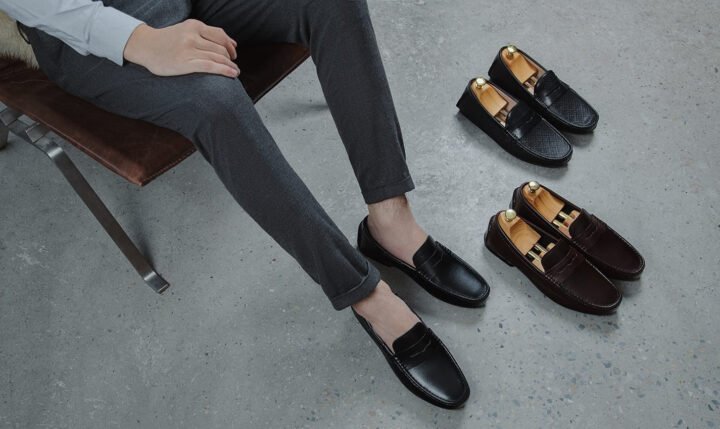 Một đôi giày lười nam đẹp màu nâu da bóng, kiểu Penny Loafer cổ điển, đặt trên nền gỗ sang trọng