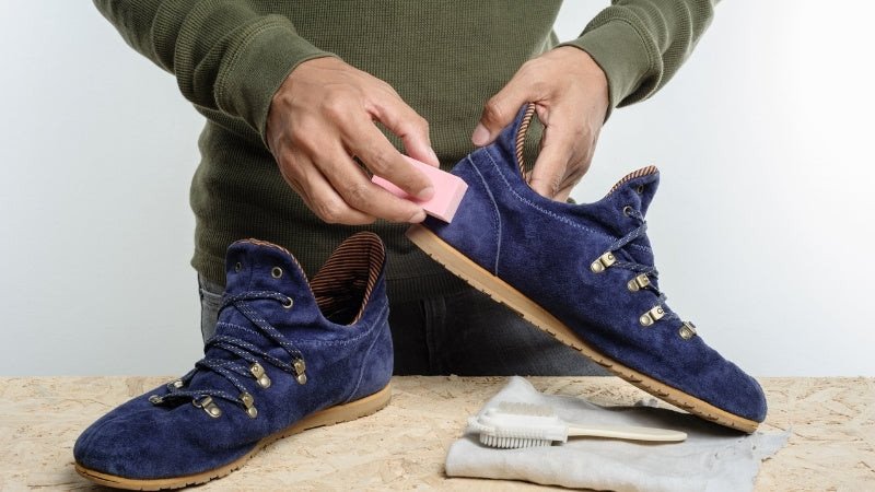 Một đôi giày sneaker da đen đang được đánh bóng bằng bàn chải mềm sau khi đã thoa xi, giúp làm mờ vết nhăn và tăng độ bền