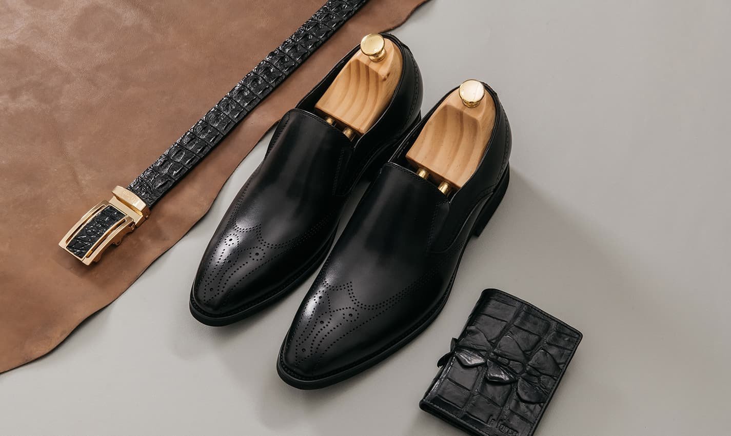 Một đôi giày tây đế cao màu đen bóng bẩy được đặt trên kệ, thể hiện sự sang trọng và chất lượng.