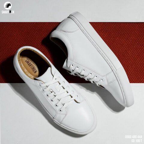 Một đôi giày thể thao trắng đặt trên sàn gỗ, phông nền đơn giản giúp nổi bật cách chụp giày thể thao đẹp.