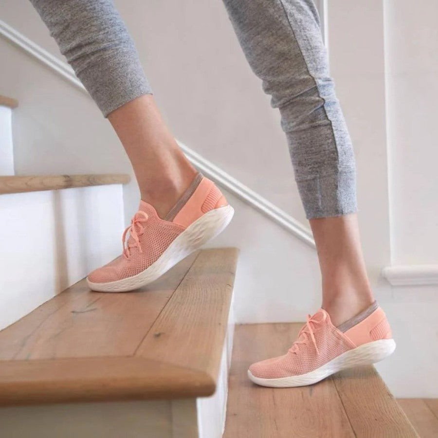 Một người đang xỏ chân vào một đôi giày sneaker màu trắng, biểu thị việc chọn giày vừa vặn sẽ giúp di chuyển thoải mái cho chân dài 24cm