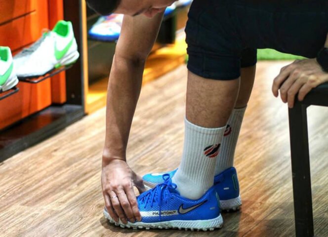 Người cầu thủ cẩn thận kiểm tra đôi giày trước khi cho vào túi đựng giày đá bóng Adidas chuyên dụng