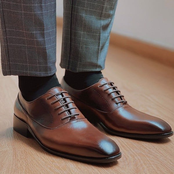 Người đàn ông mặc vest màu xám than lịch lãm, phối cùng giày Oxford màu đen cổ điển, toát lên vẻ chuyên nghiệp