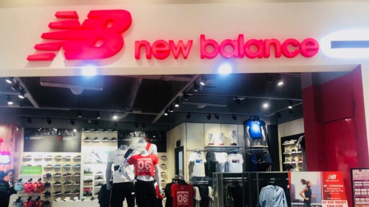 Người mẫu nữ trẻ trung mặc trang phục street style, đội mũ lưỡi trai và đi giày New Balance màu sáng, tạo dáng năng động trên phố Hà Nội.