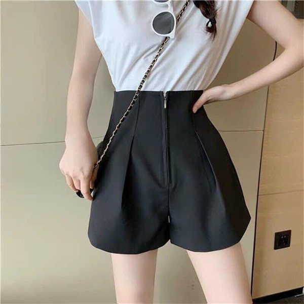 Người phụ nữ mặc quần short cạp cao màu xanh denim và áo sơ mi trắng đơn giản
