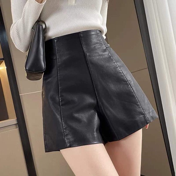 Người phụ nữ mặc quần short da đen bóng và áo len dệt kim