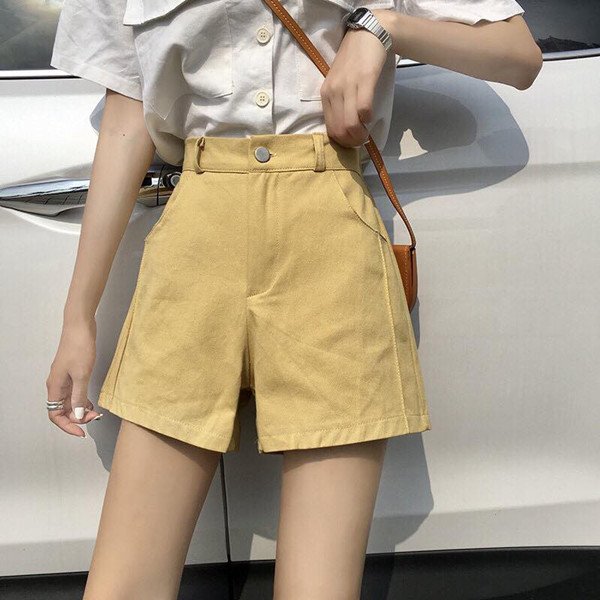 Người phụ nữ mặc quần short kaki màu be và áo sơ mi trắng đơn giản