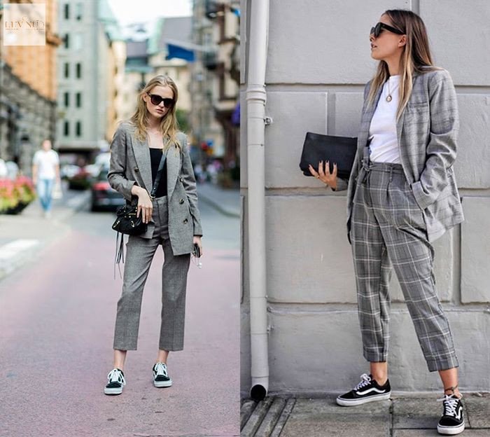 Người phụ nữ mặc vest xám kẻ sọc và quần âu, phối với giày sneaker trắng