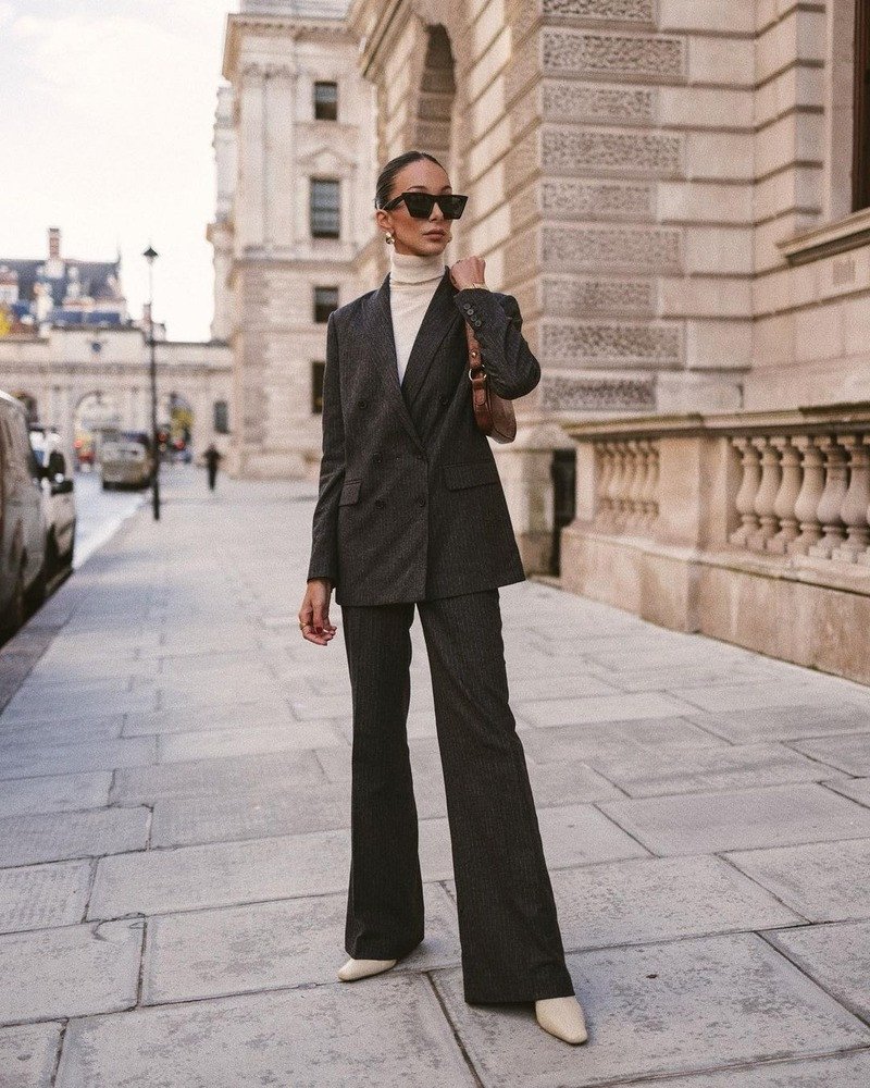 Nữ giới mặc vest đen phối chân váy ngắn và boot cổ cao mũi nhọn