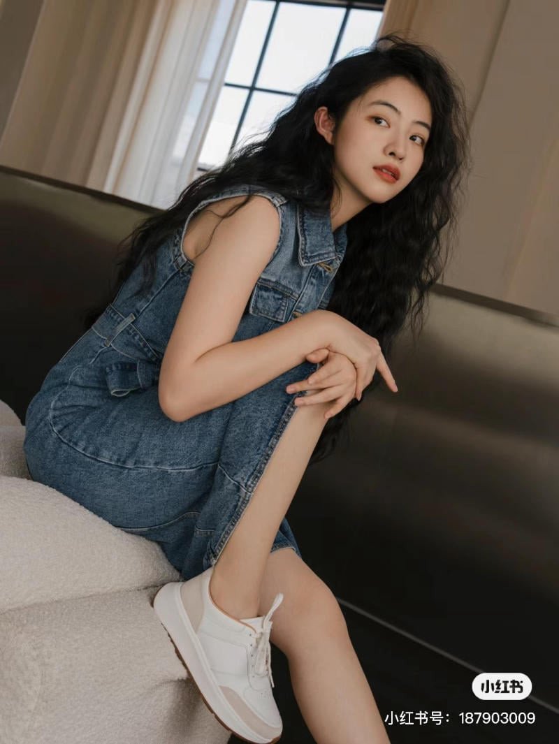 Phụ nữ mặc váy denim dài ôm dáng và giày sneaker đen