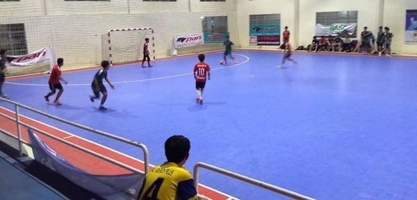 Sân bóng đá trong nhà với cầu thủ di chuyển trên nền gỗ phẳng