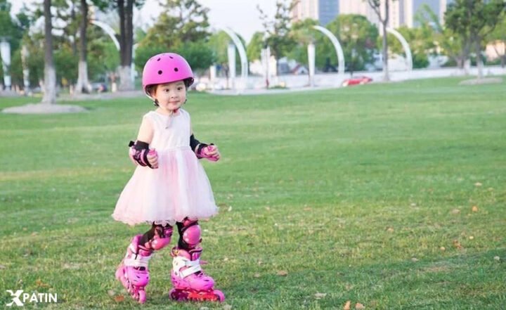 Trẻ em gái đội mũ bảo hiểm và bảo hộ, đang tập trượt giày patin Flying Eagle S5S màu hồng