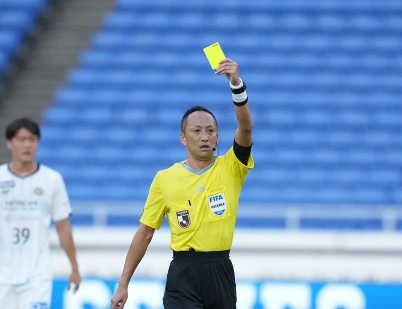 trọng tài giơ tay ra hiệu trong trận đấu, cho thấy sự linh hoạt và hỗ trợ từ giày trọng tài bóng đá