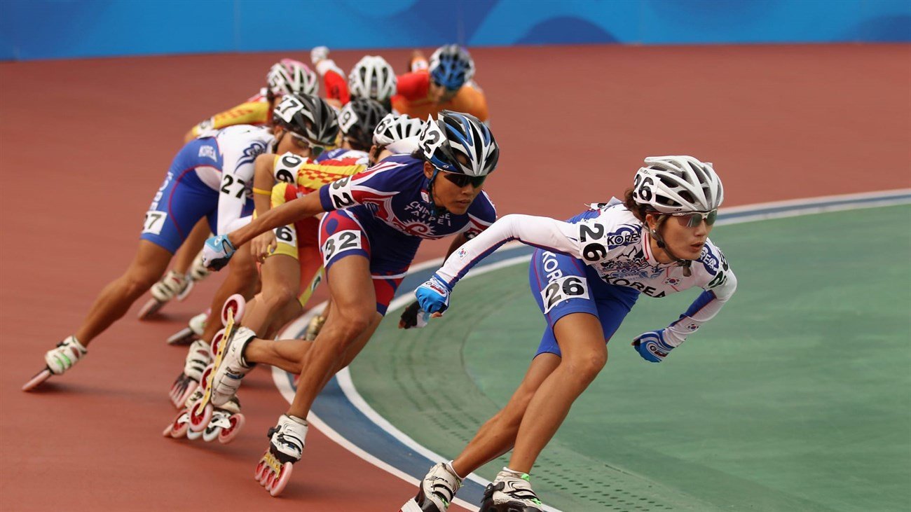 Vận động viên đang thực hiện kỹ năng trượt patin tốc độ cao (Inline Speed Skating) với giày thể thao chuyên dụng trên đường đua.